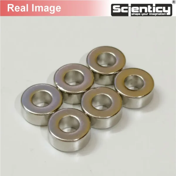 Real product photograph of six silver 11mm x 5mm x 5mm neodymium ring magnets with center holes from Scienticy.