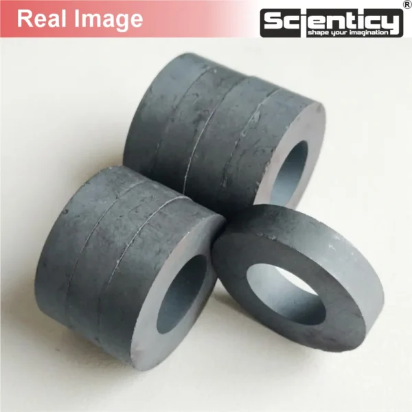 A stack of real circular black ceramic ferrite ring magnets shown from a close-up angle.